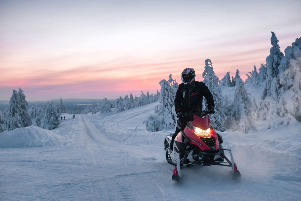 Elev som övningskör på Luleå trafikskolas röda skoter i vinterlandskap